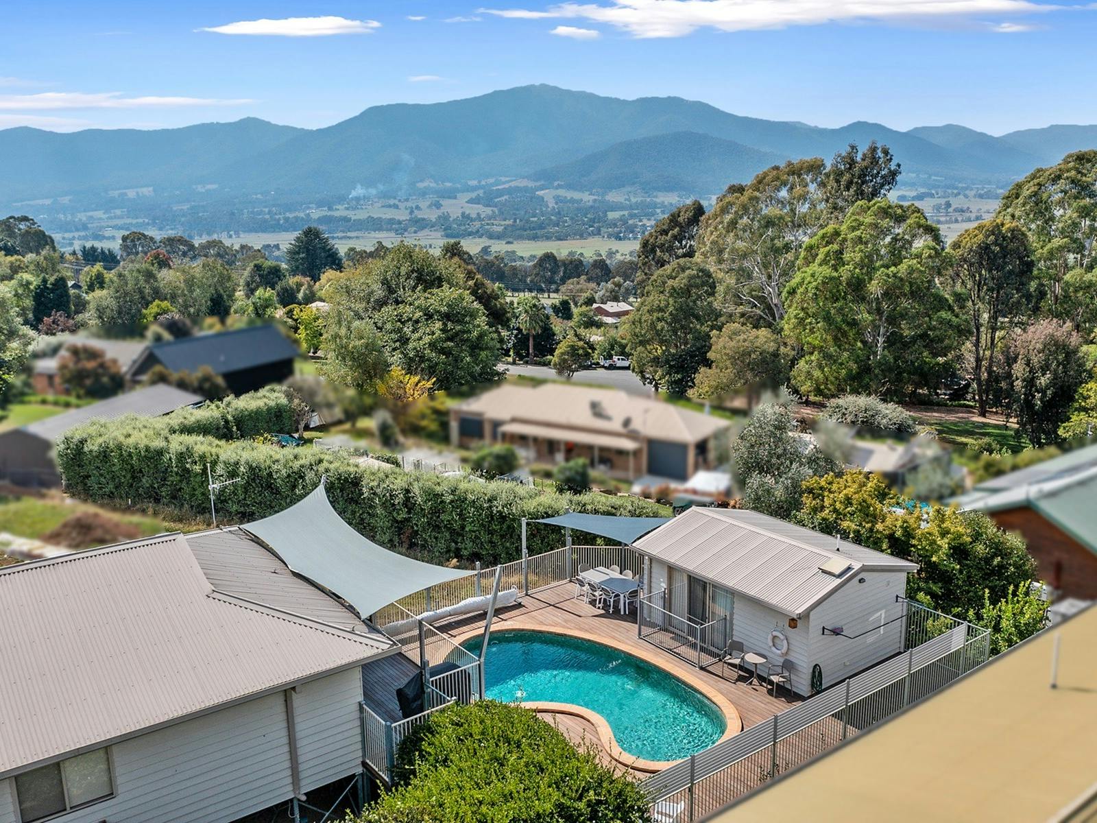 Arial shot of the house with the swimming pool in view and mountains and other houses in the back