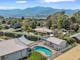 Arial shot of the house with the swimming pool in view and mountains and other houses in the back
