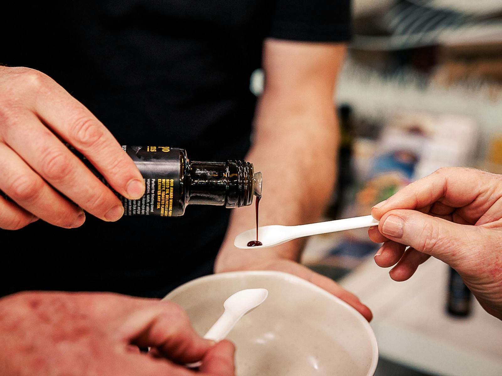 Pumpkin seed oil being poured onto spoons for sampling by guests