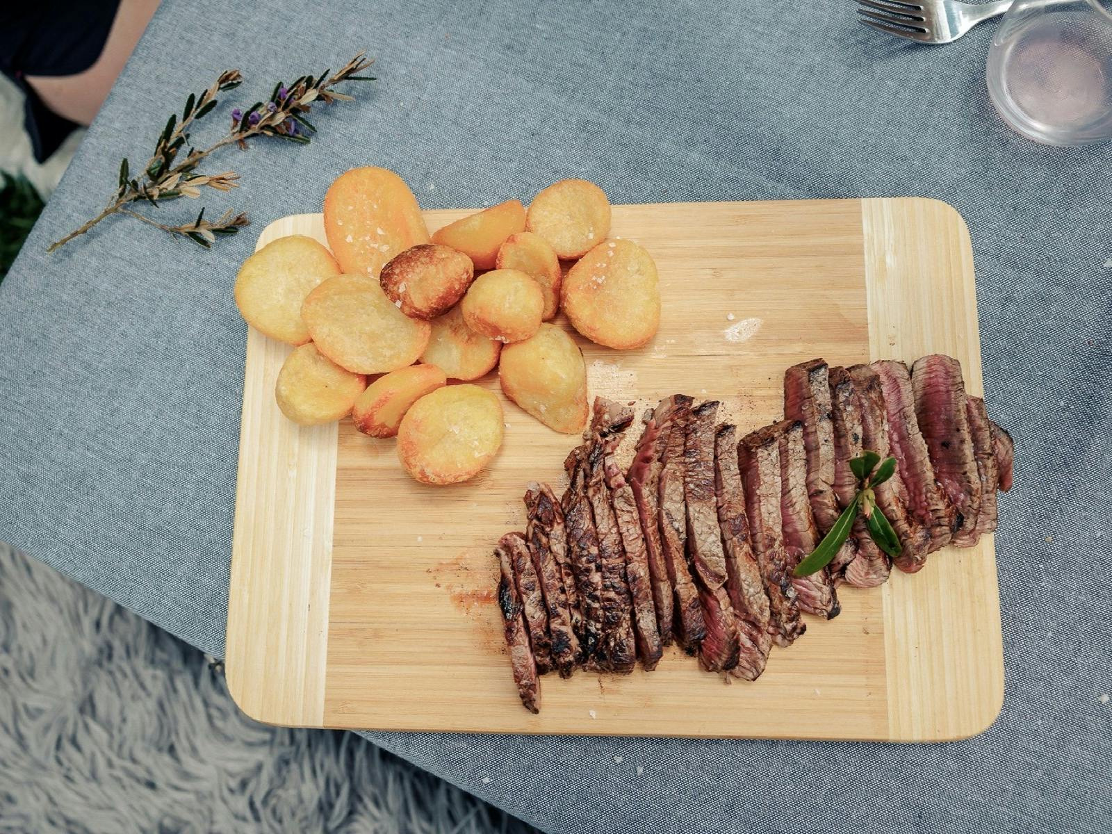Wooden board with meat and potatoes