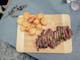 Wooden board with meat and potatoes