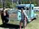 Two people standing next to a teal coloured truck