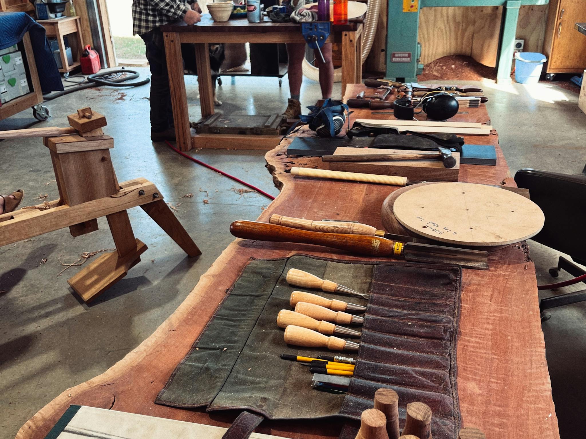 Chisels and handtools in the foreground and people making stools in the background