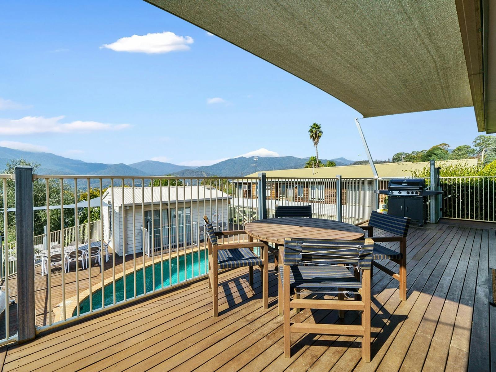 Balcony shot overlooking an outdoor swimming pool and mountains in the background