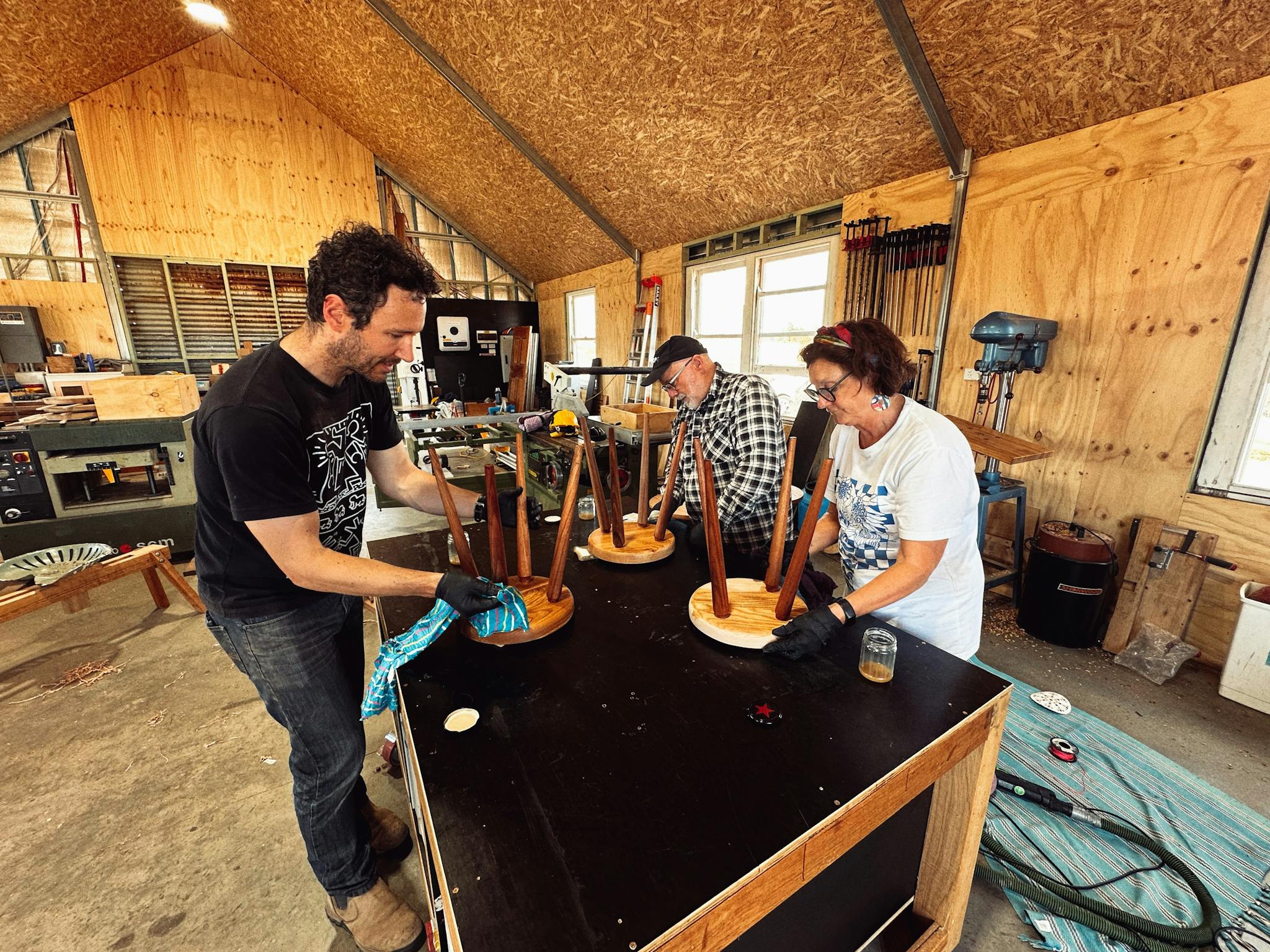 Three participants oiling their stools on a bench