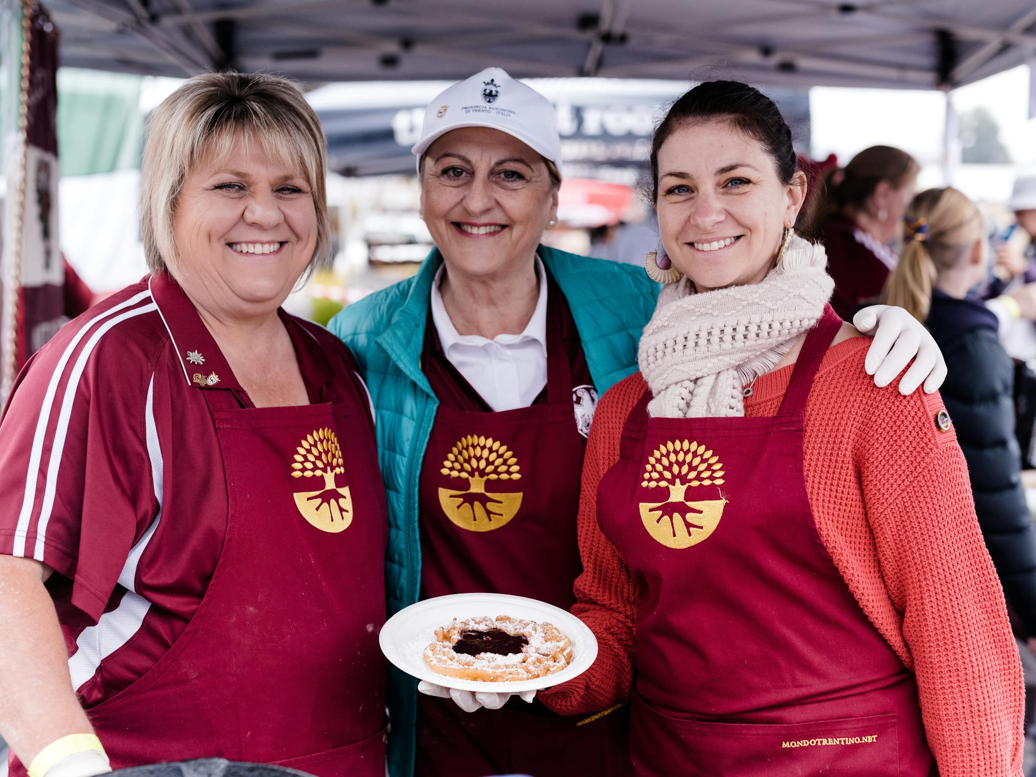three women posing with food on a plateTrentini delicacy - Strauben