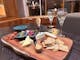 Cheeseboard with crackers, cheese, dips and forks in the cheese, with two glasses of champagne