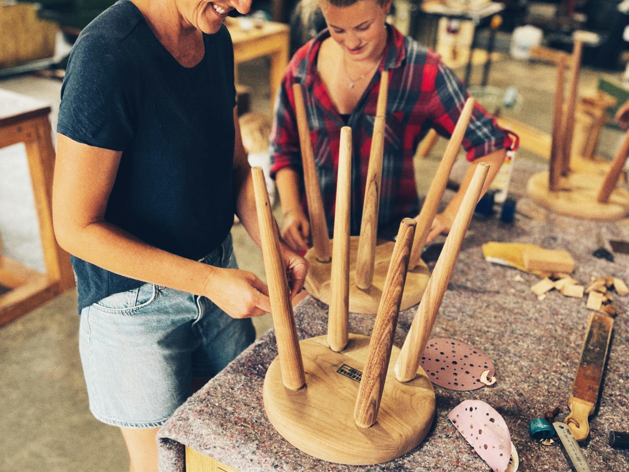Two people assembling their four legged stools