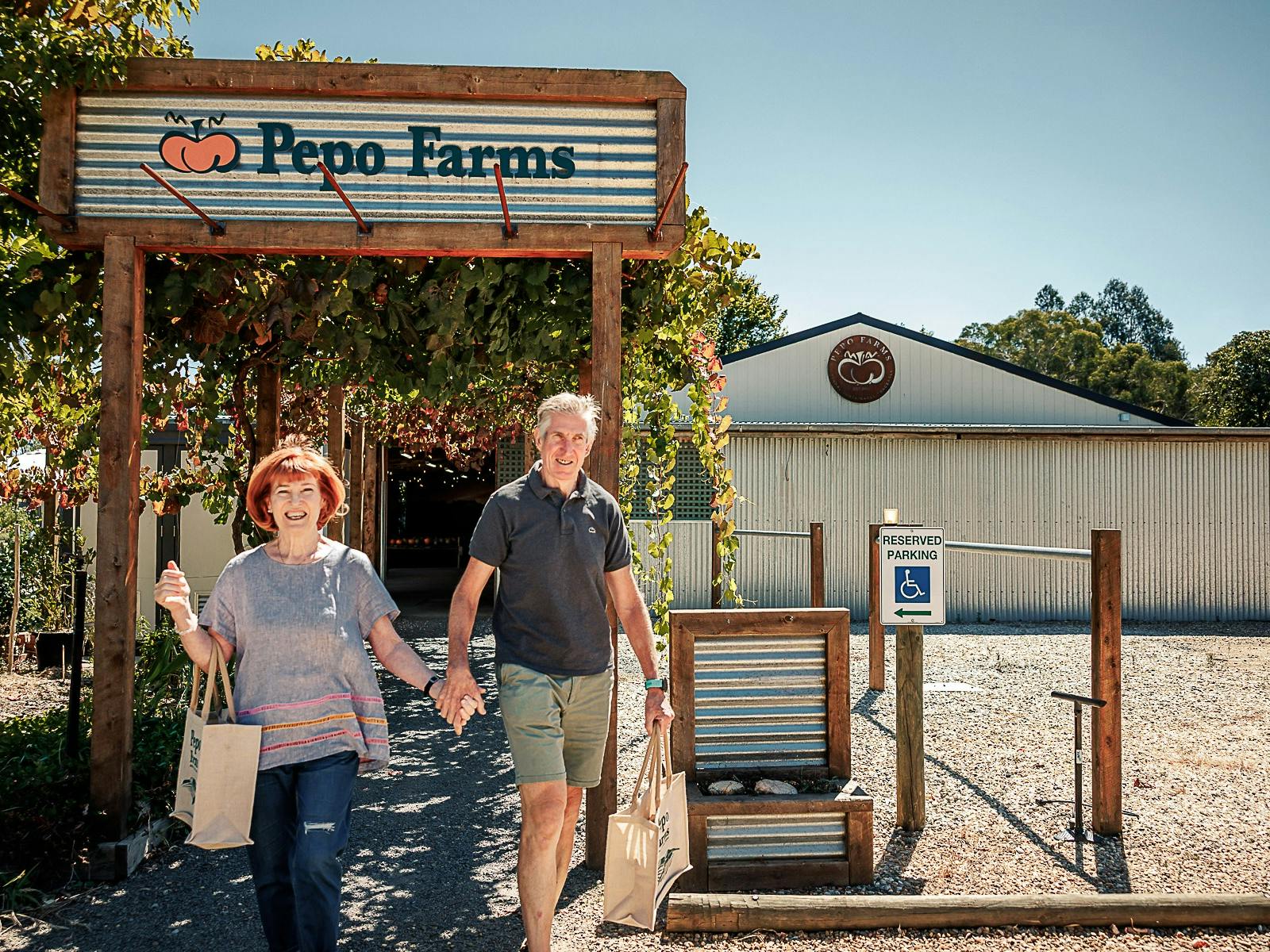 Couple with bags of product walking from shop to carpark at Pepo Farms