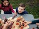 Wooden boards with assorted meats and two children eating