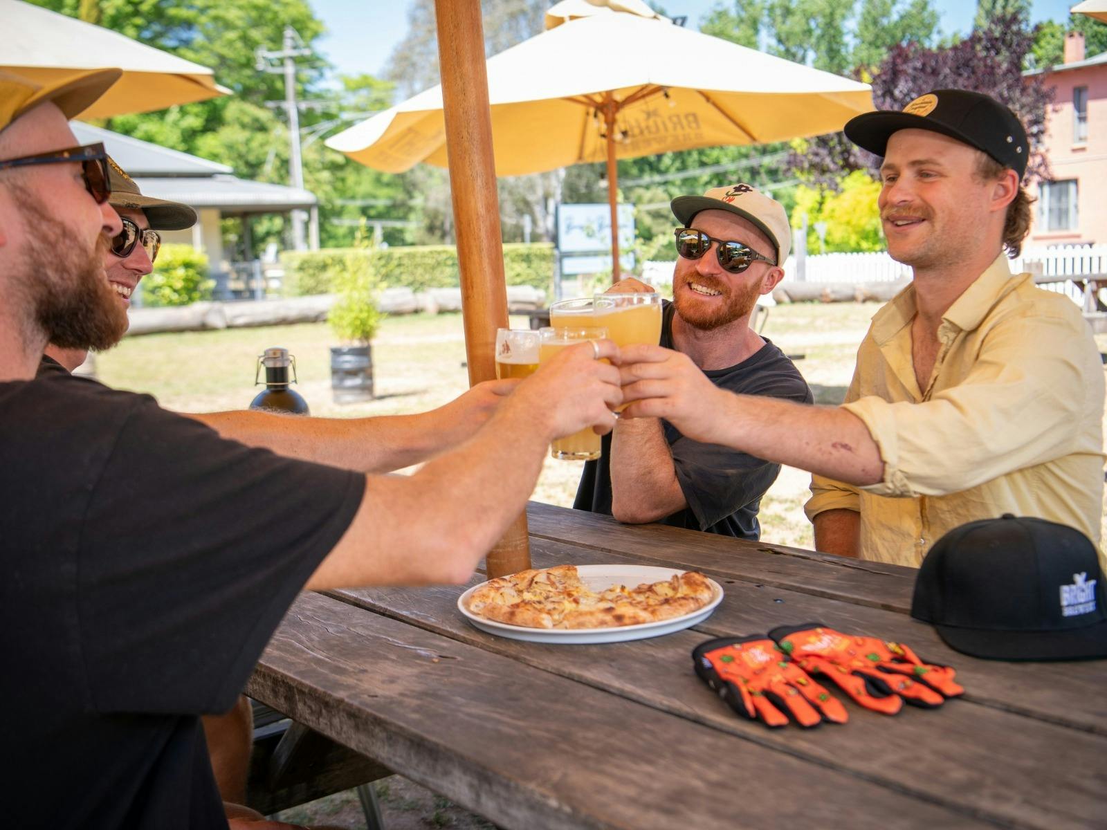 Friends clinking beer glasses over a pizza