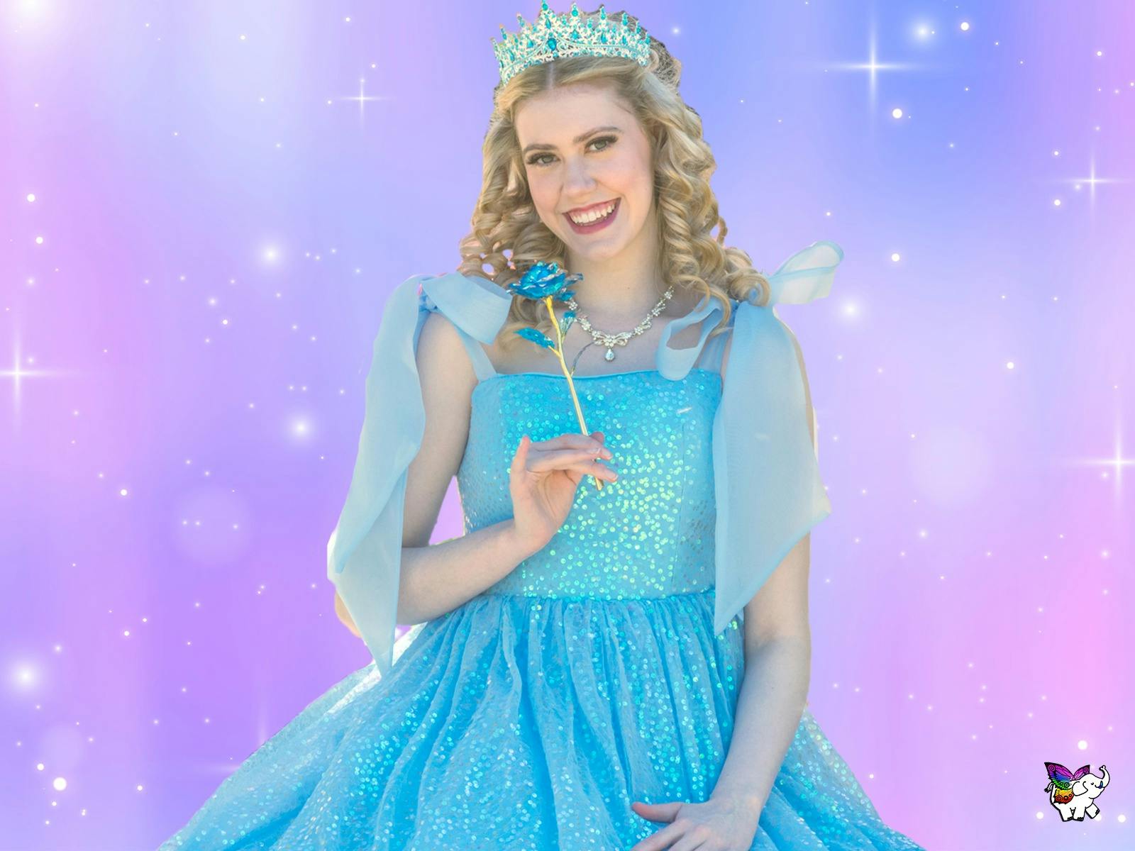 A lady dressed in a sparkly blue dress stands against a pink and purple background, smiling