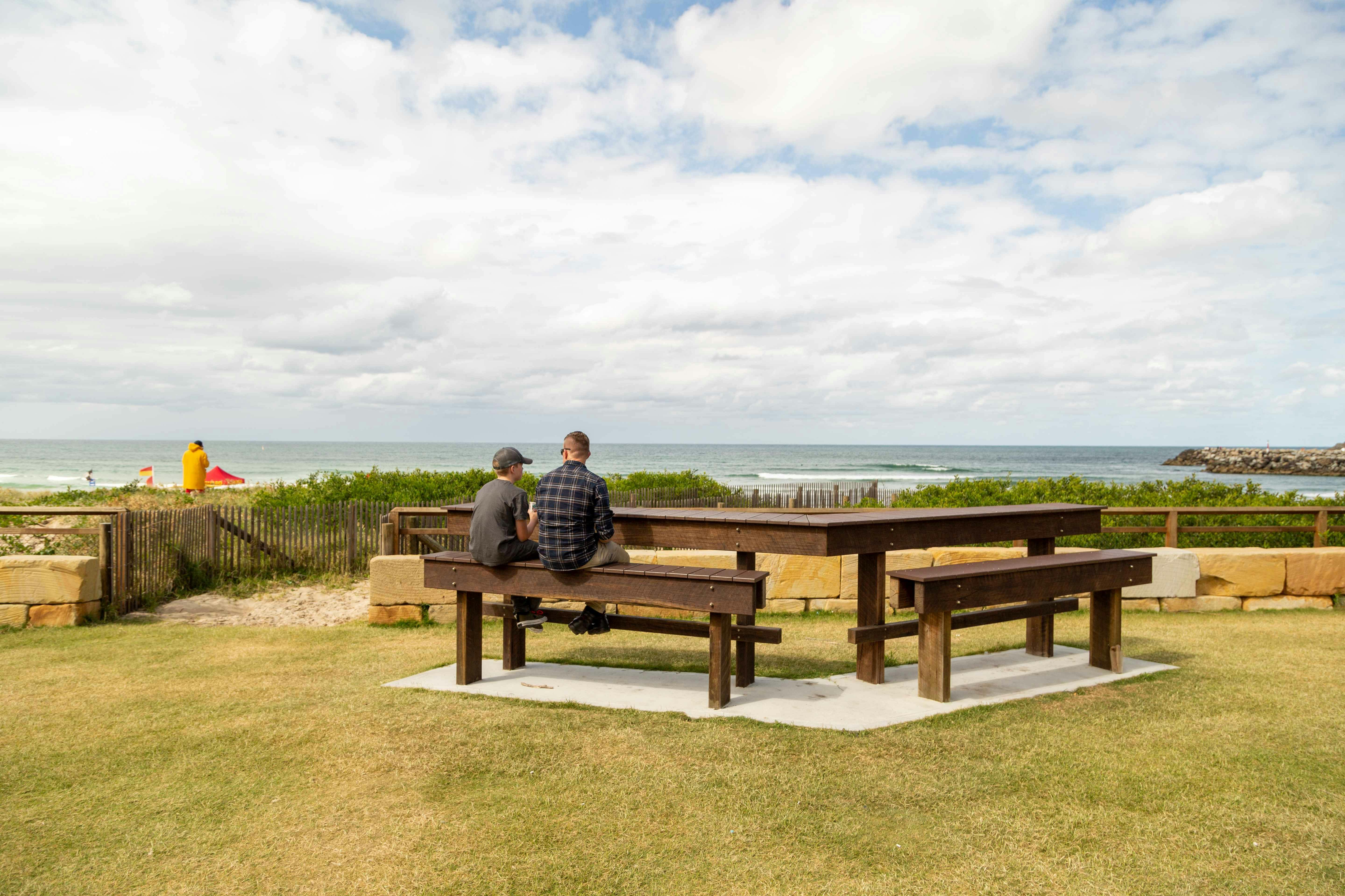 Father and son sitting on benches at the beach.