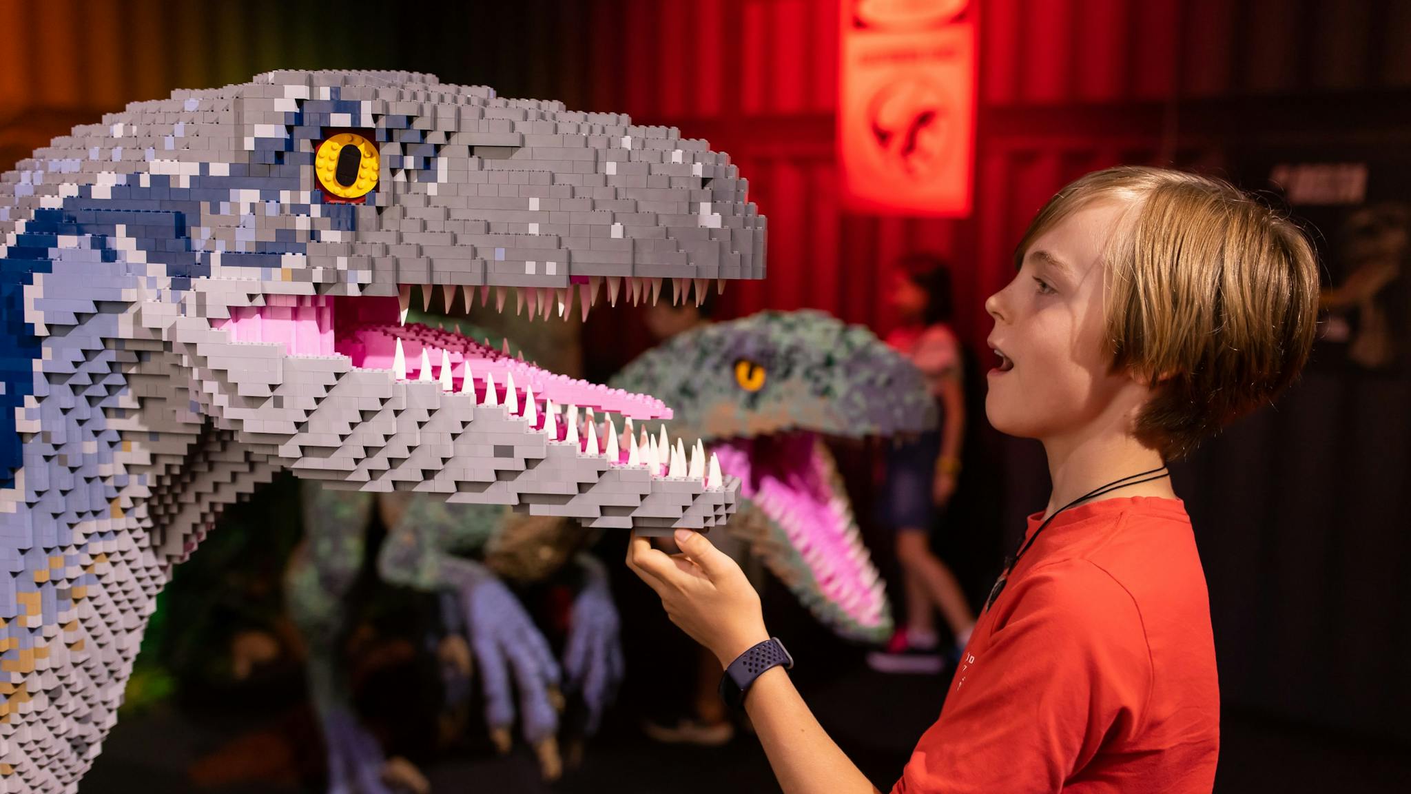 A child facing a LEGO brick velociraptor