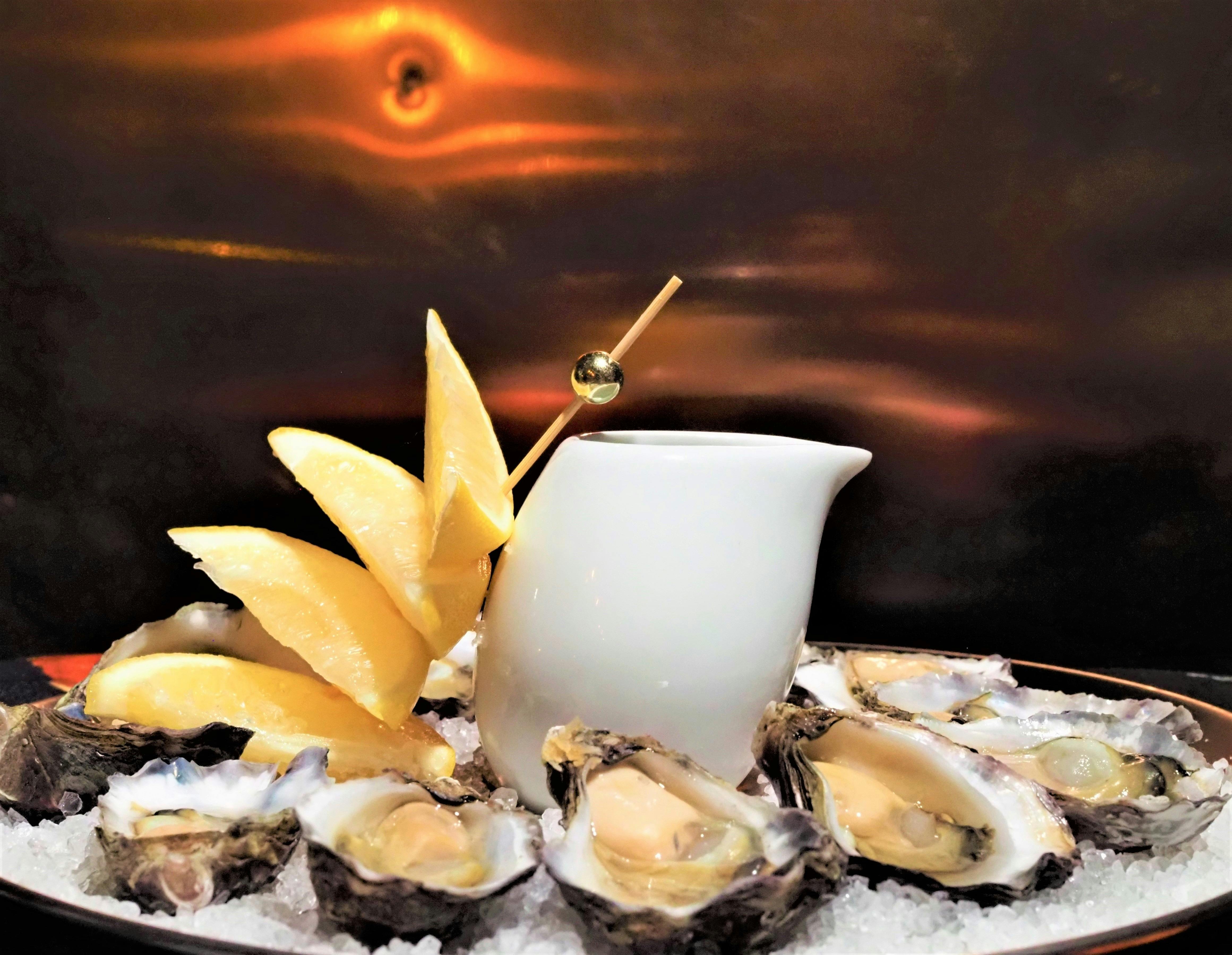 12 Oysters with Lemons stacked vertically in front of a copper wall on The Floating Oyster Wine Bar.