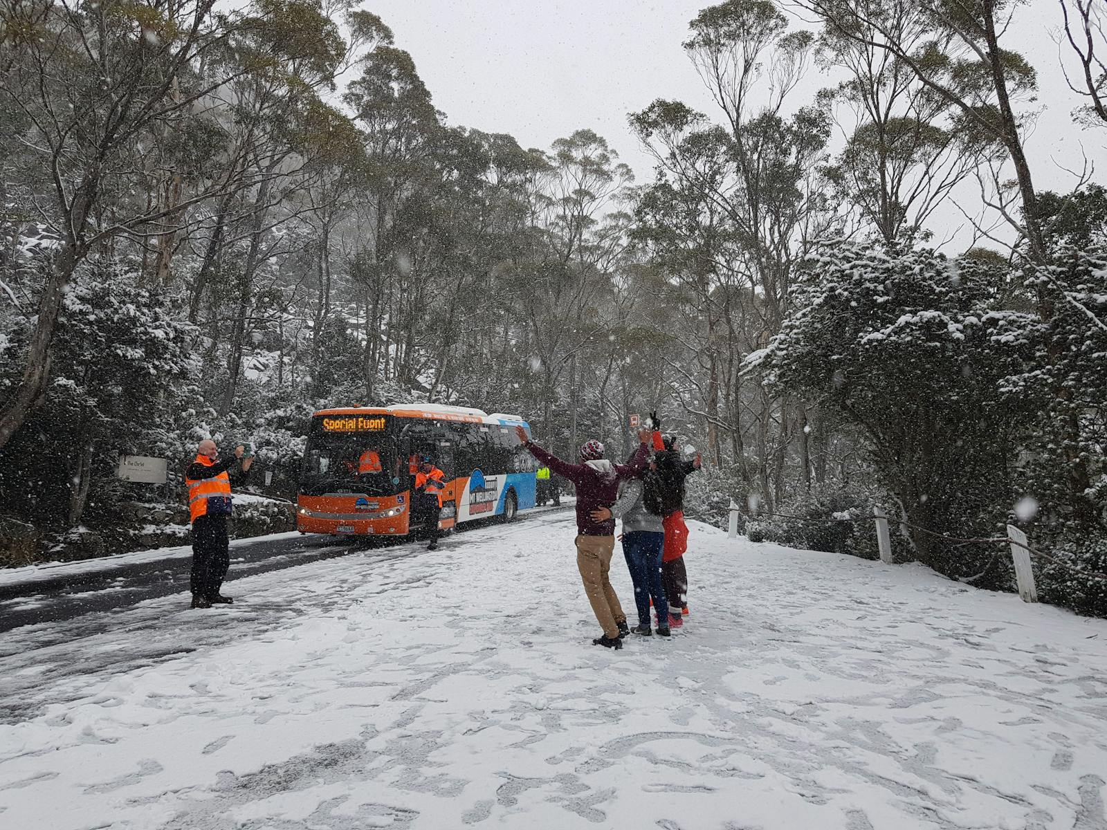 Passengers playing in the snow. Bus in the background.