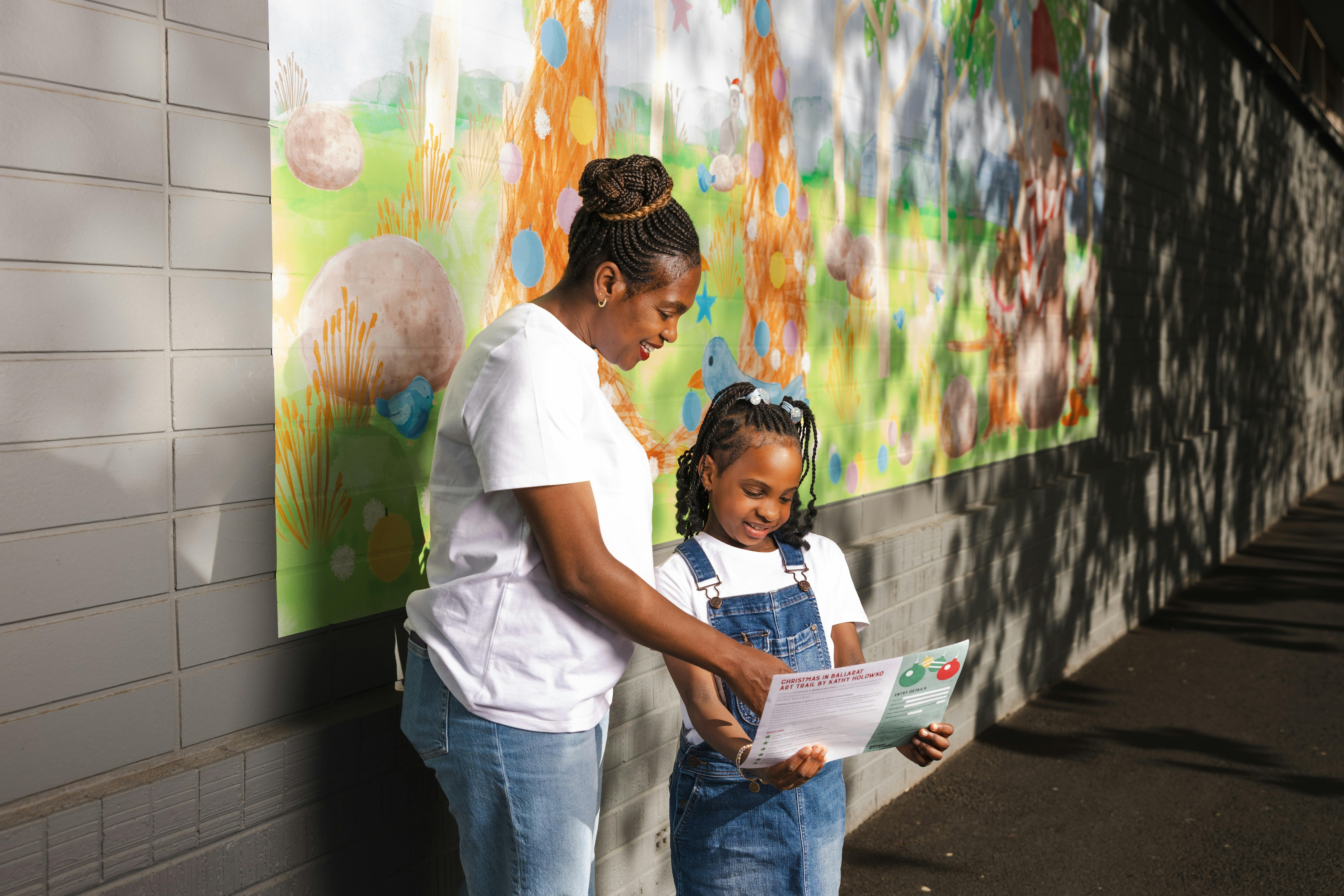 Adult & child reading map in front of artwork