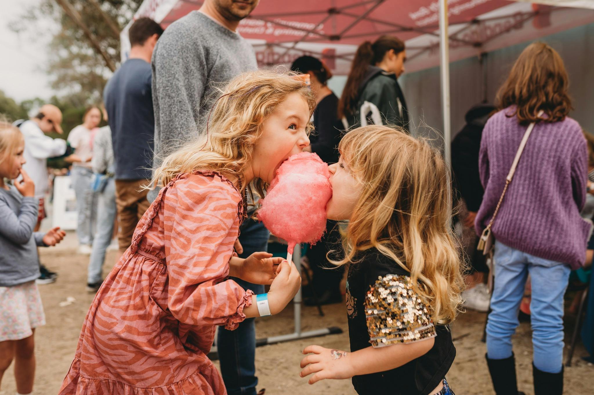 Two children sharing bright pink fairy floss