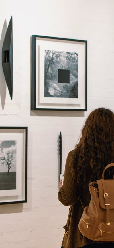 Two women are looking at framed photographs on the gallery wall