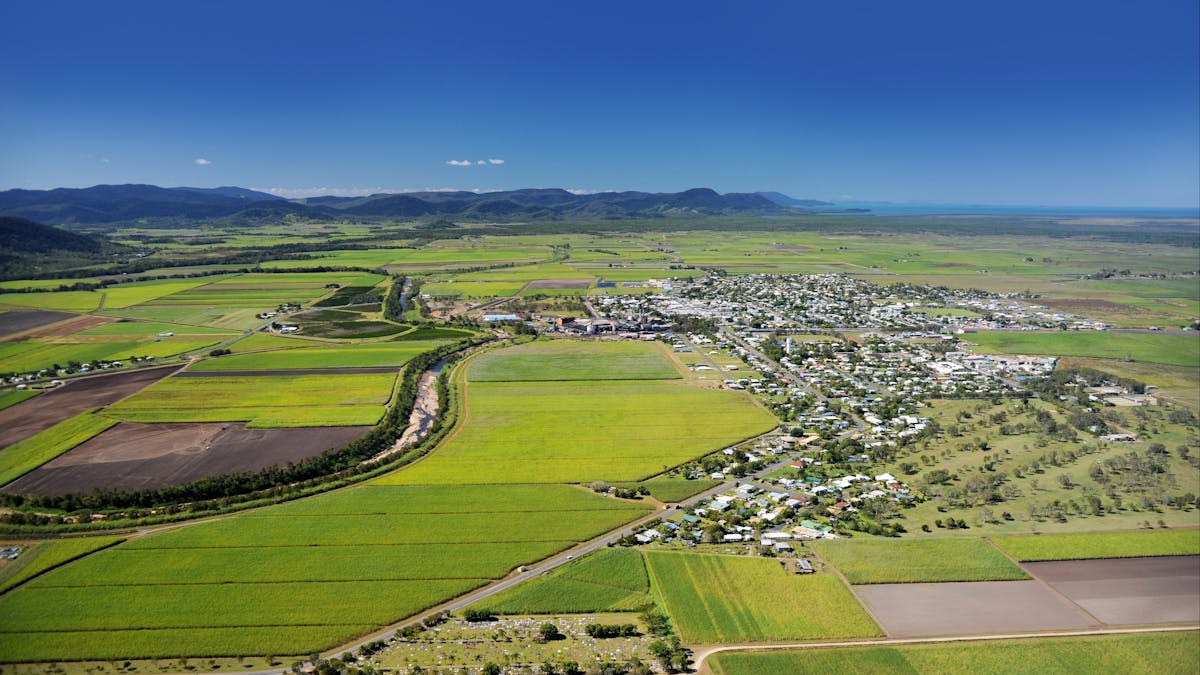 Aerial view of a small town surrounded with green fields and mountain range