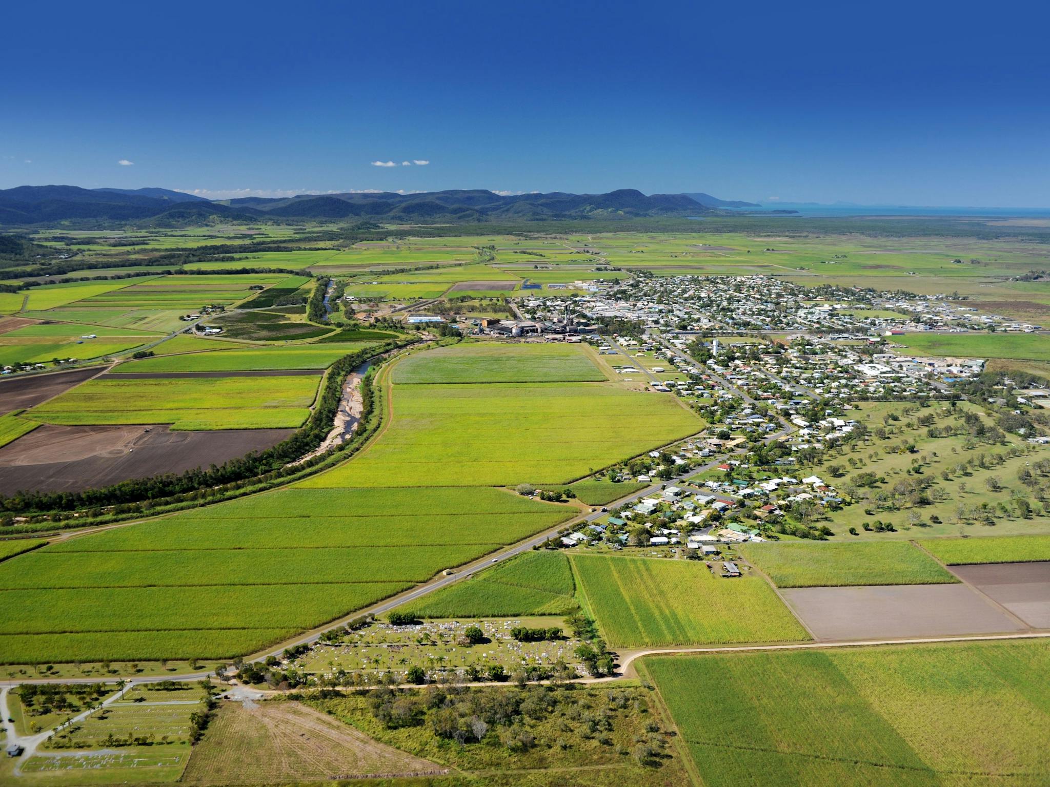 Aerial view of a small town surrounded with green fields and mountain range