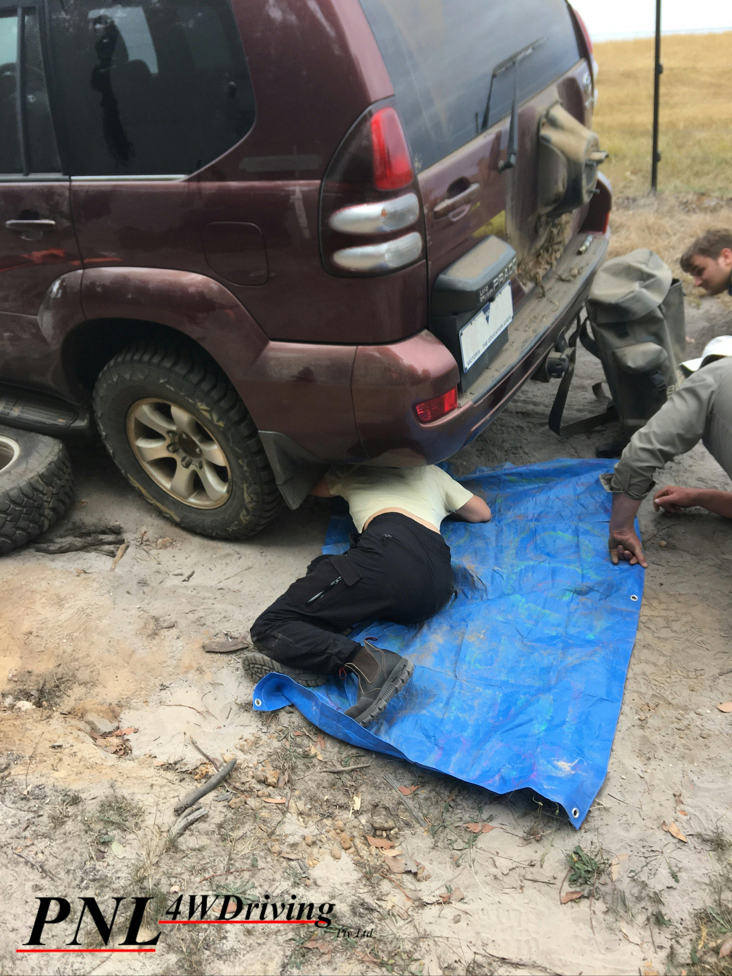 A participant checks underneath their car