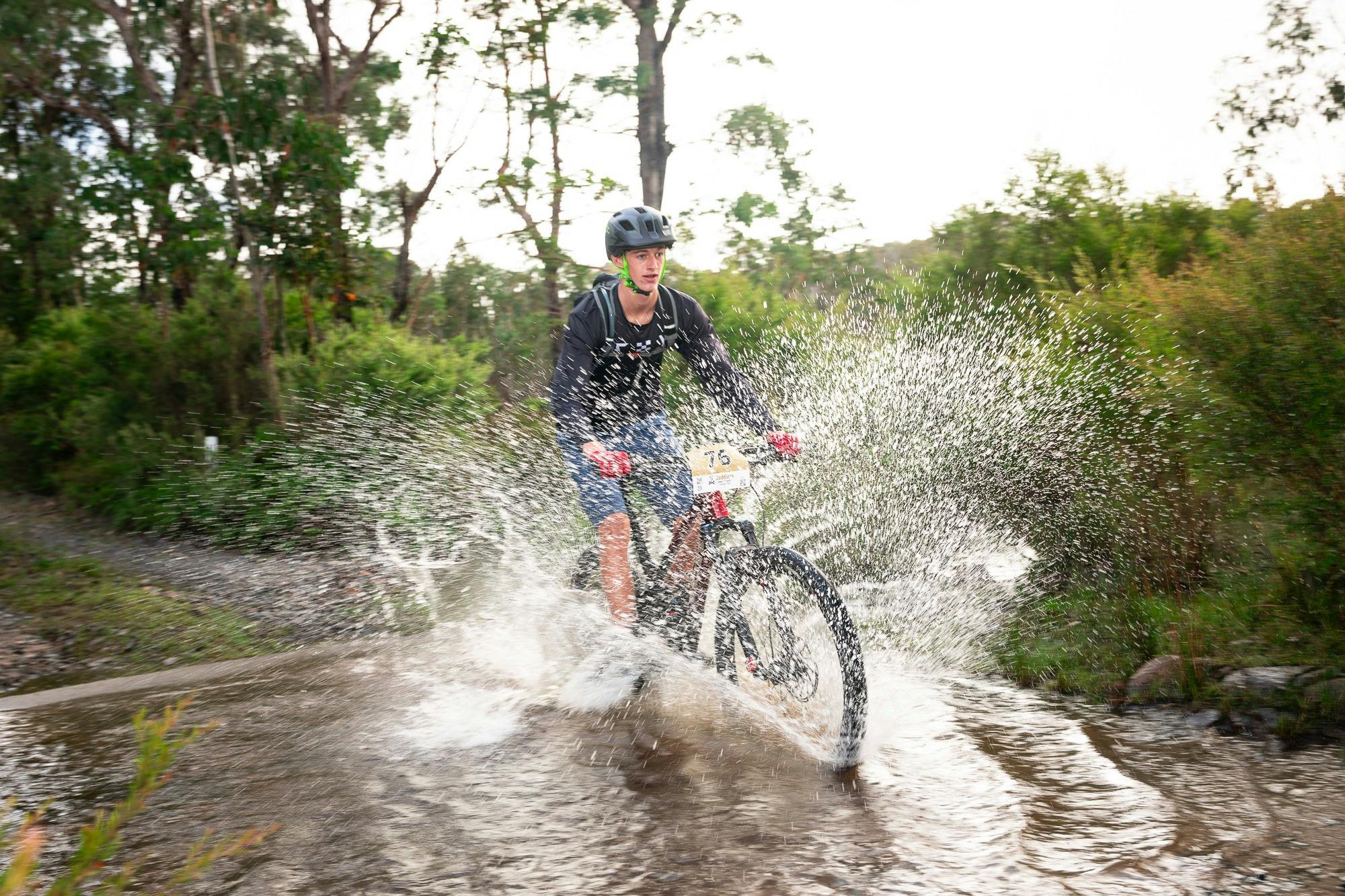 Rider crosses water crossing with large splash of water