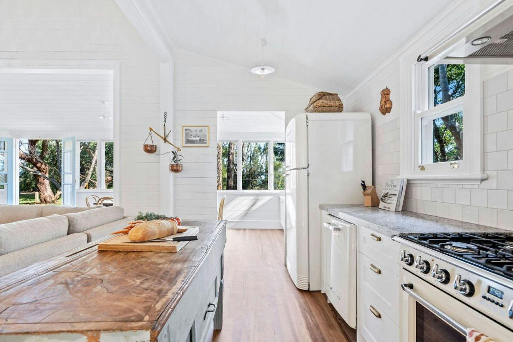Image of renovated kitchen. Large wooden island bench. Fully equipped kitchen in white.