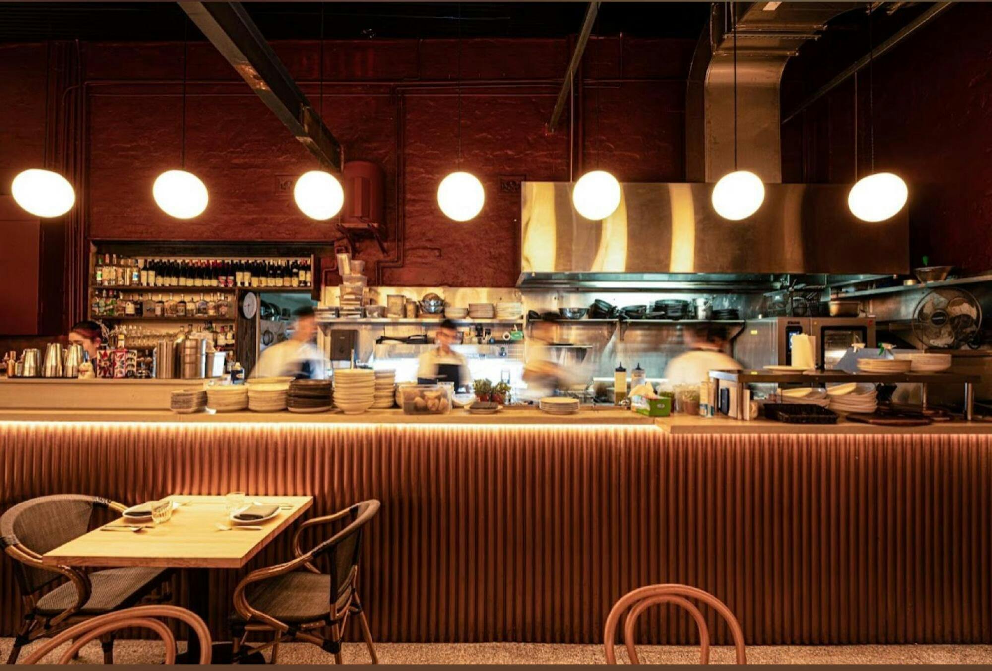 The image features the bustling, open kitchen of Warike restaurant with blurred chefs at work, under