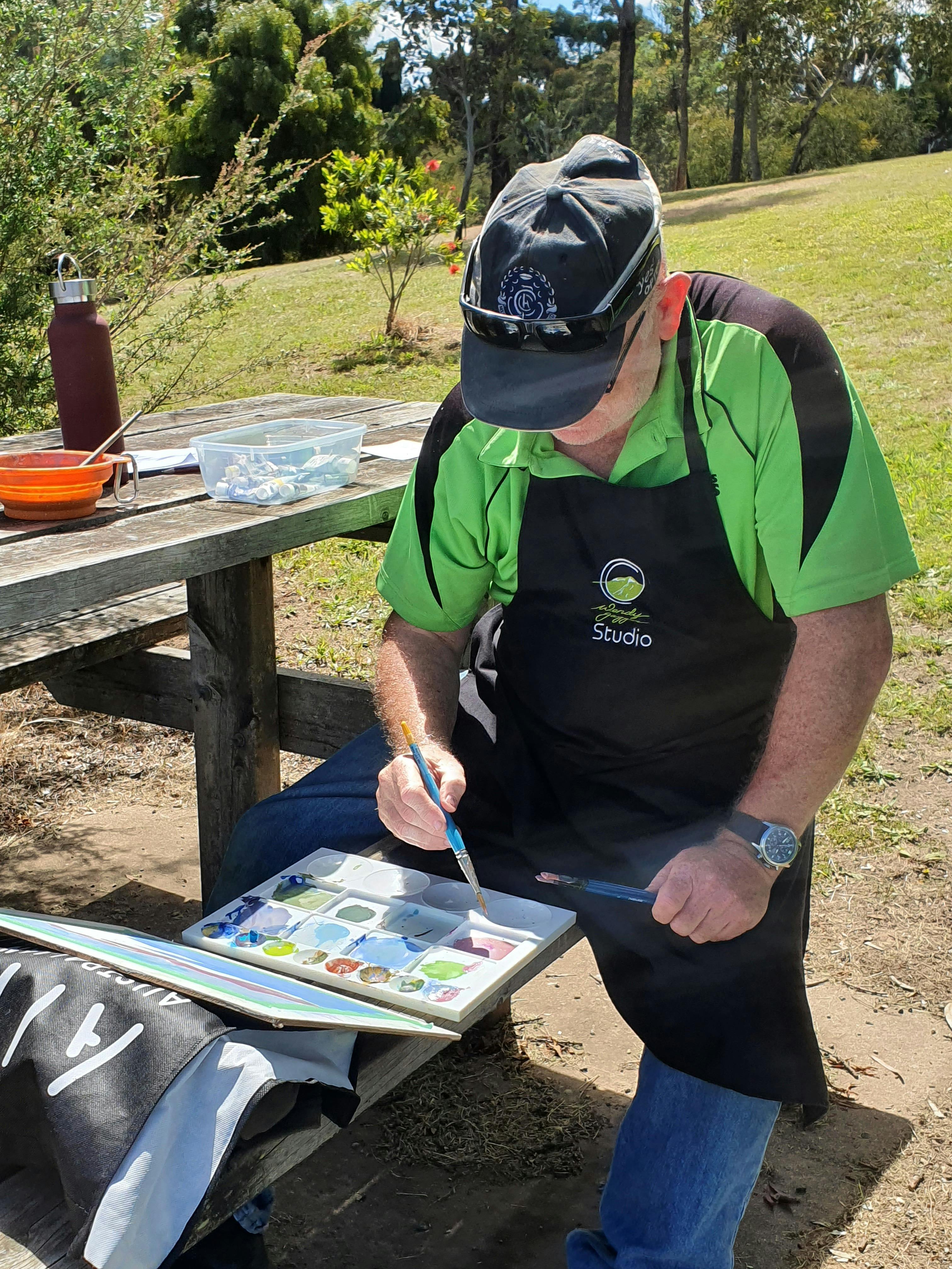 A man painting onto watercolour paper in Wendy Jagger Studio class.