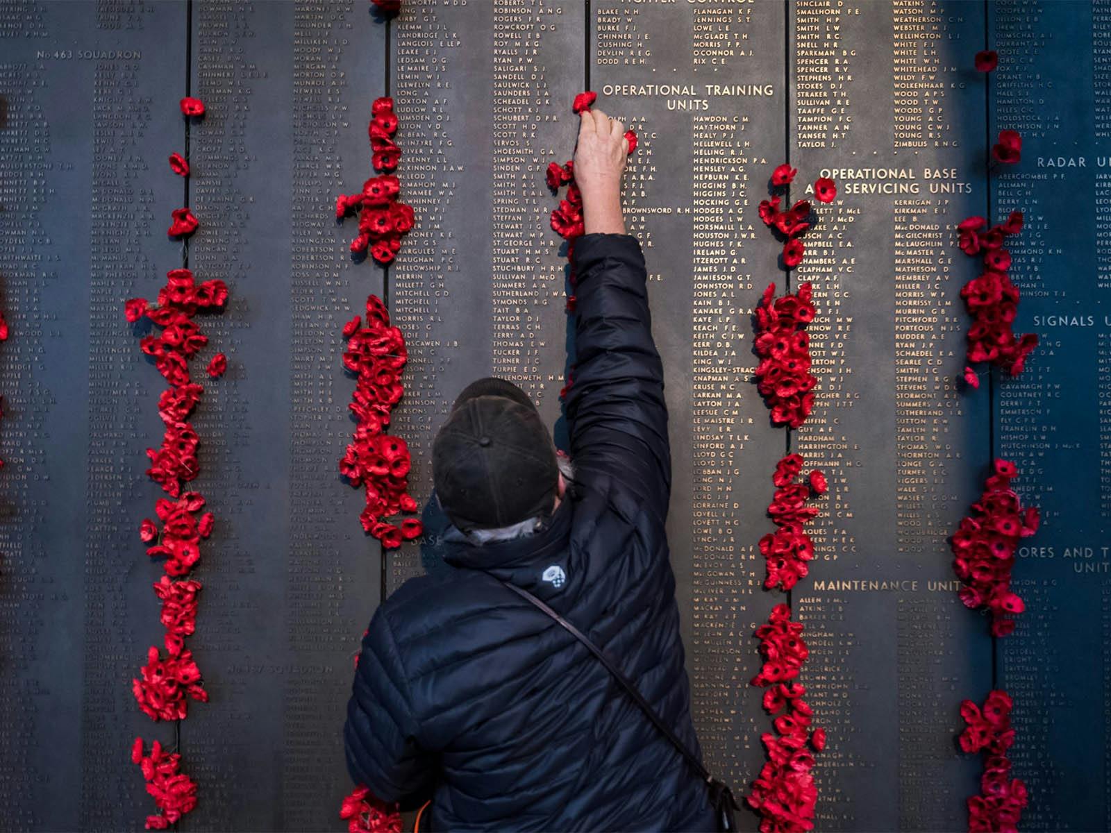 man places poppy on Roll of Honour