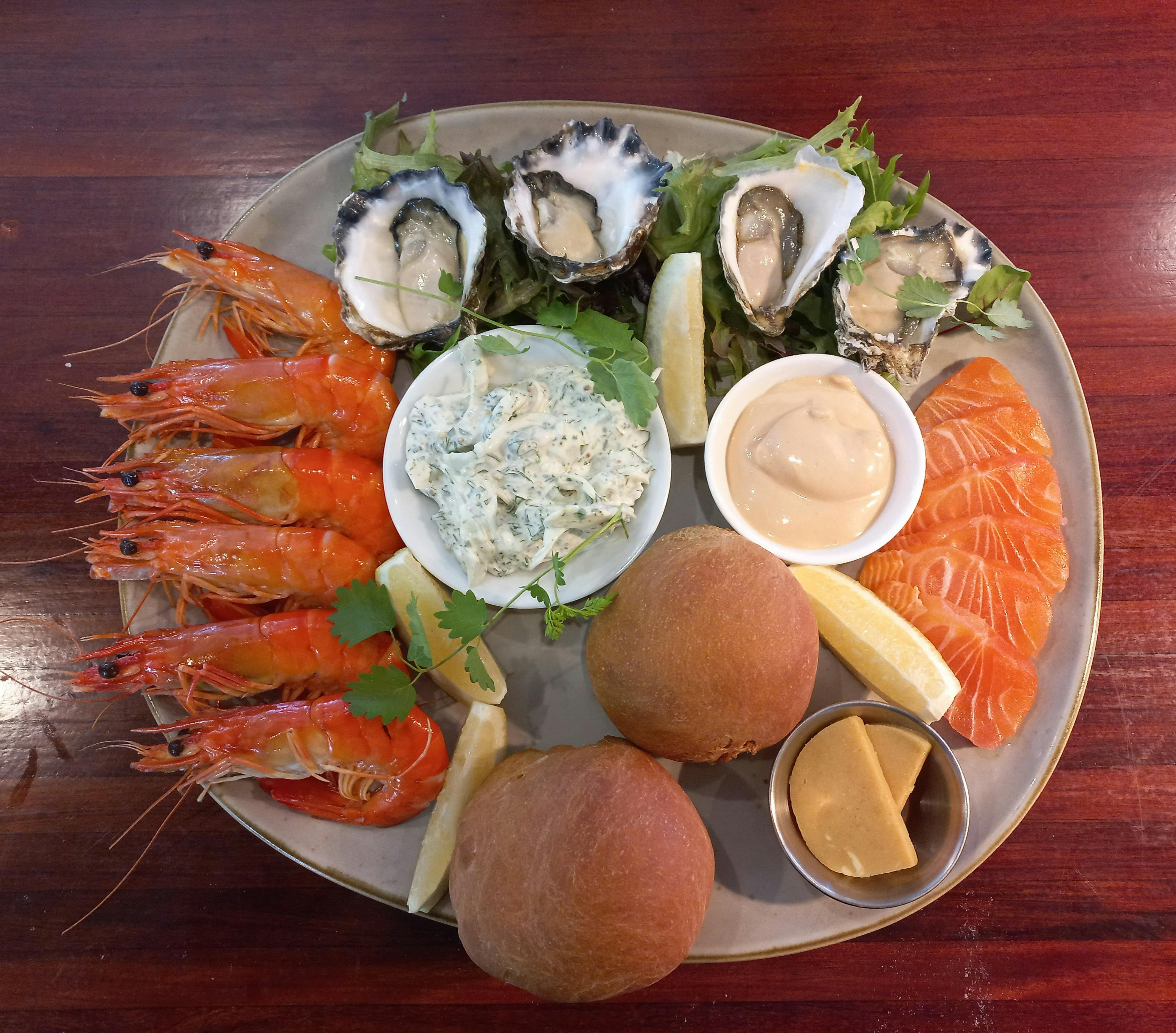 冷たいシーフードプレート、エビ、牡蠣、塩漬けサーモン、温かいロールパン