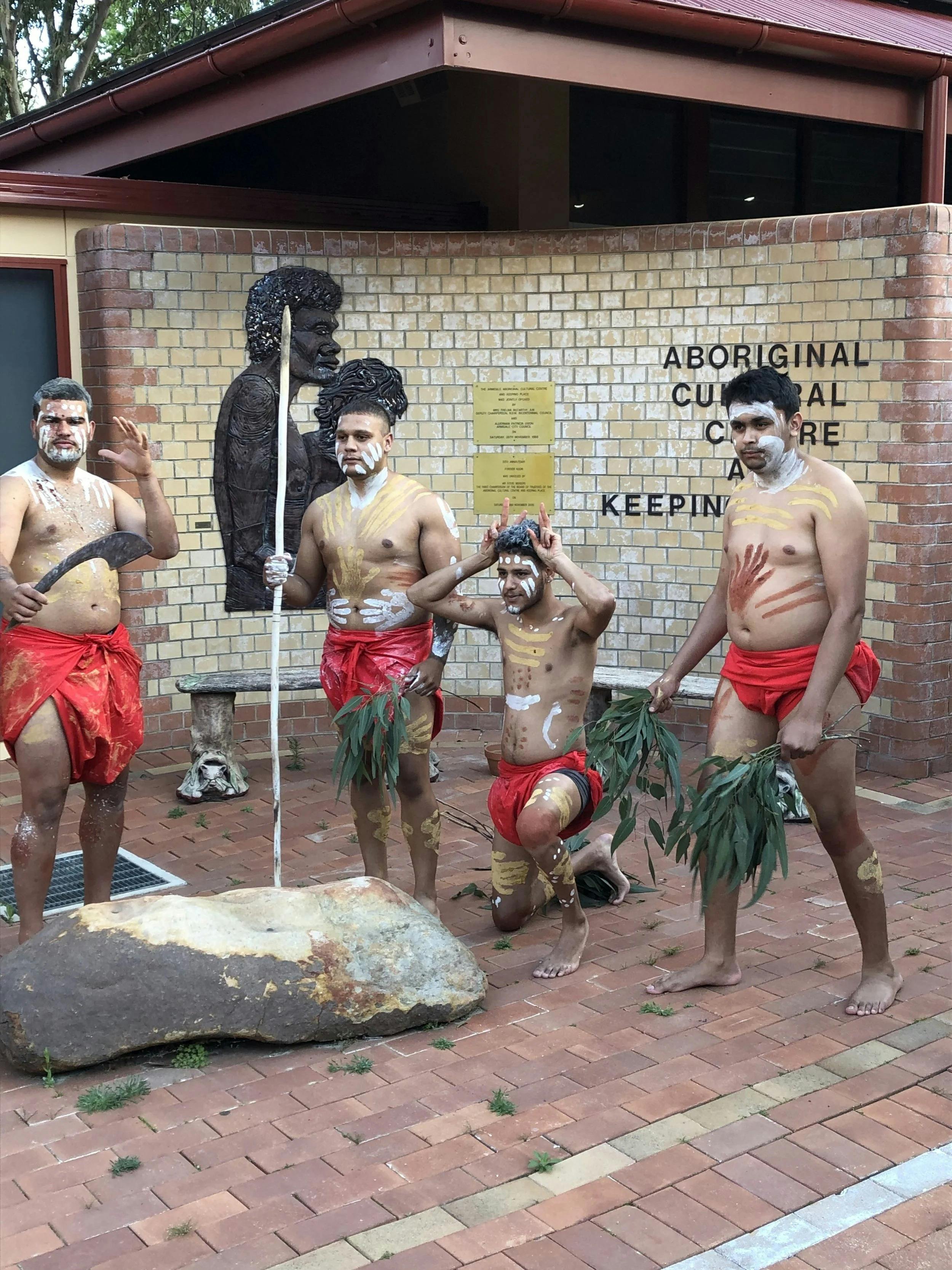 Four Aboriginal Dancers pose in front of ACCKP sign
