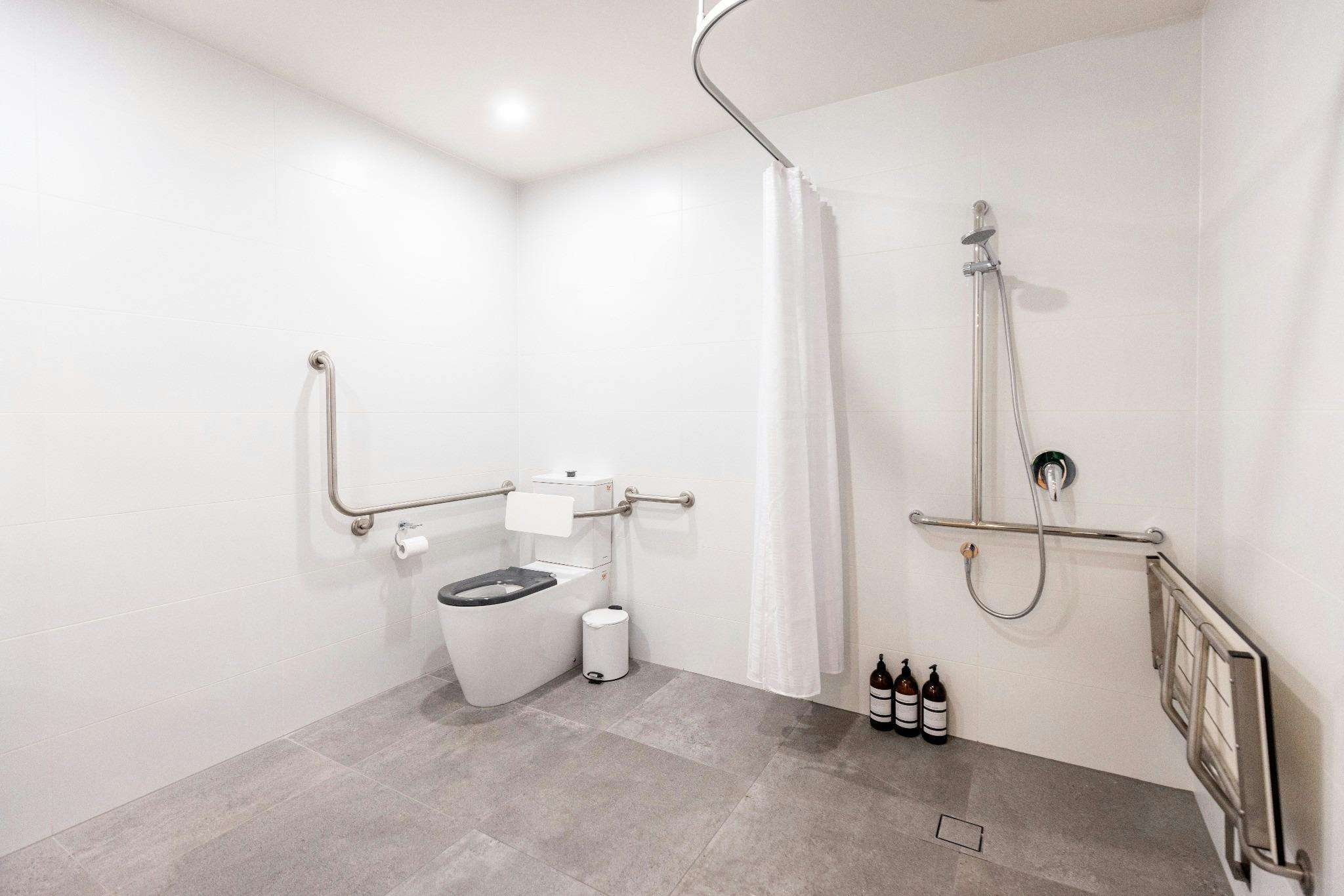 Generously sized accessible bathroom featuring grab rails, step-free shower access