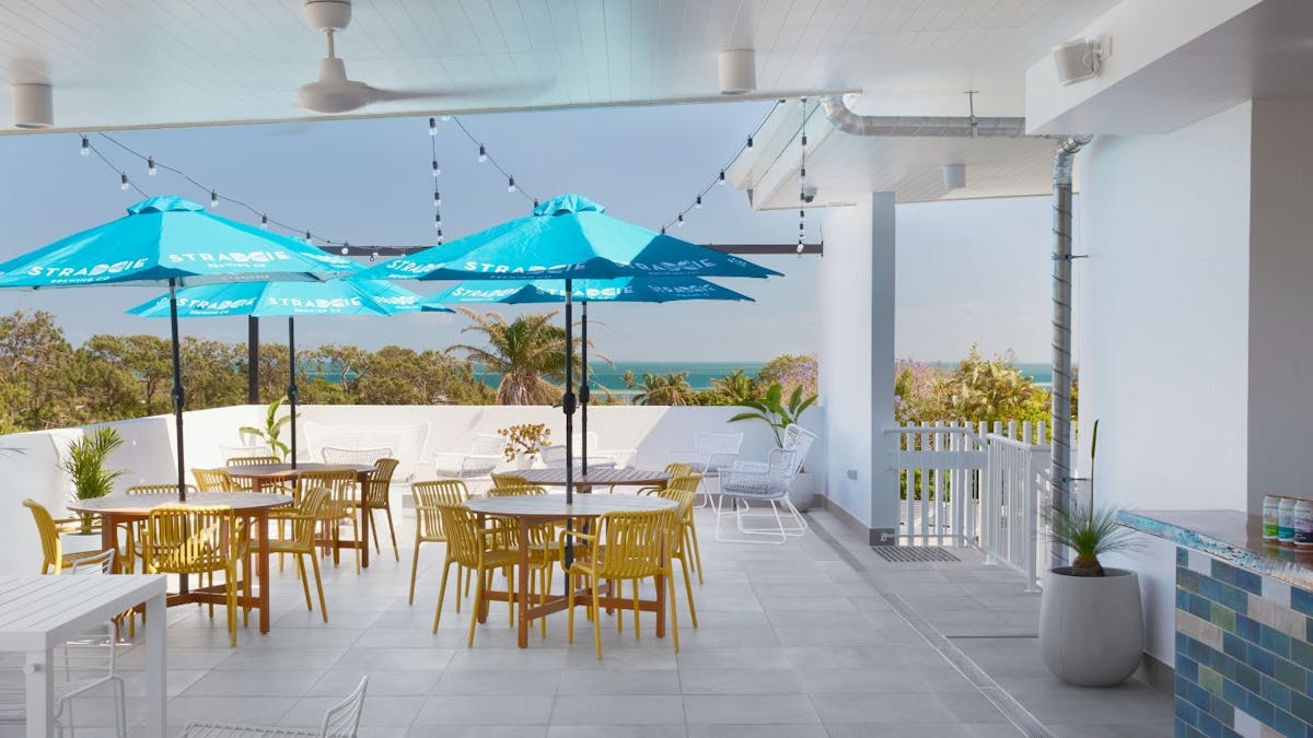 Rooftop Bar with round tables, blue umbrellas and yellow chairs
