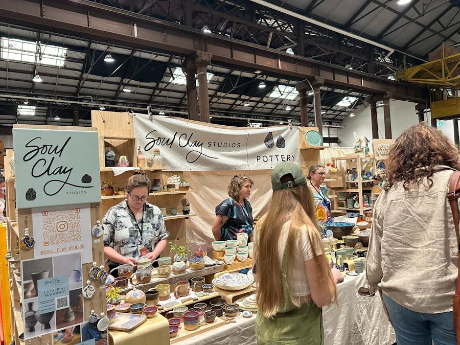 People standing behind a market stall counter and other people walking in front