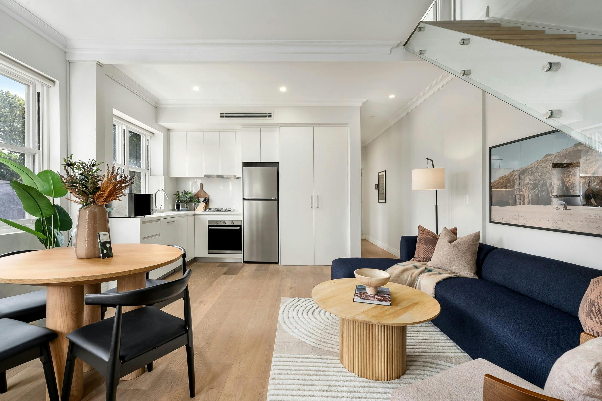 Spacious, double storey living area with modern kitchen appliances, couch and dining area.