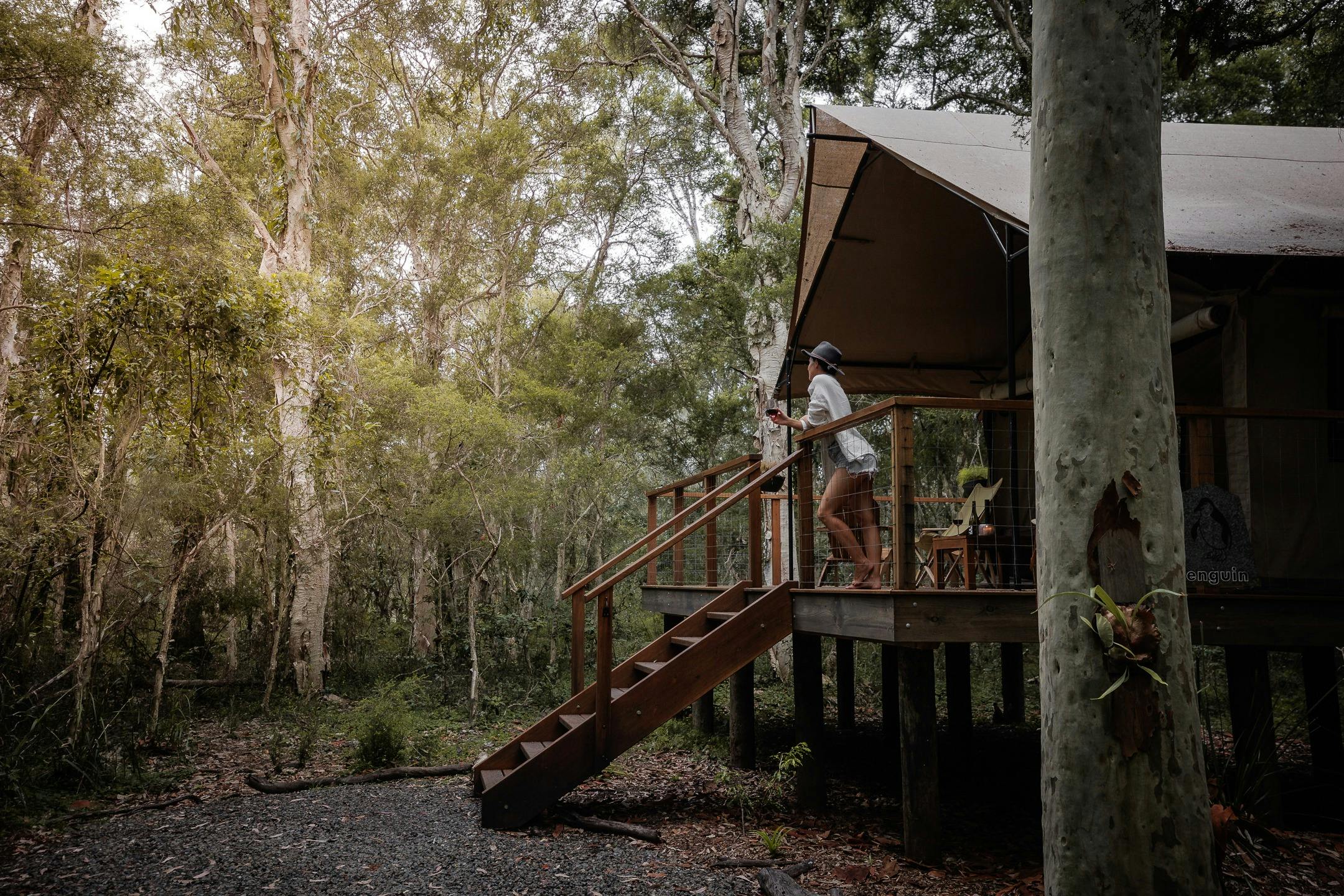 Safari tent and woman looking out to bush surrounds from verandah