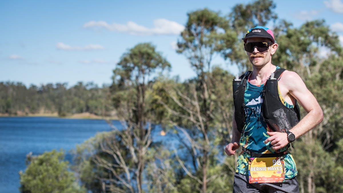 A runner smiles as he passes Lake Manchester on the 100km course