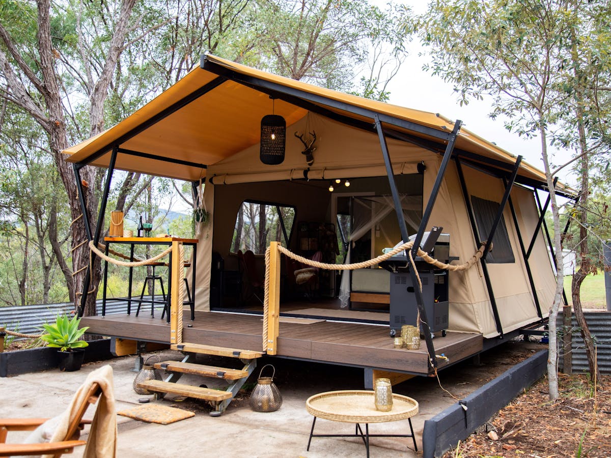 a picture of a luxury safari tent with deck and stairs set in a bush setting