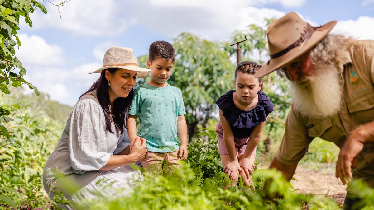 Ross leads a family and children through lush garden beds at High Valley Dawn Permaculture Farm.