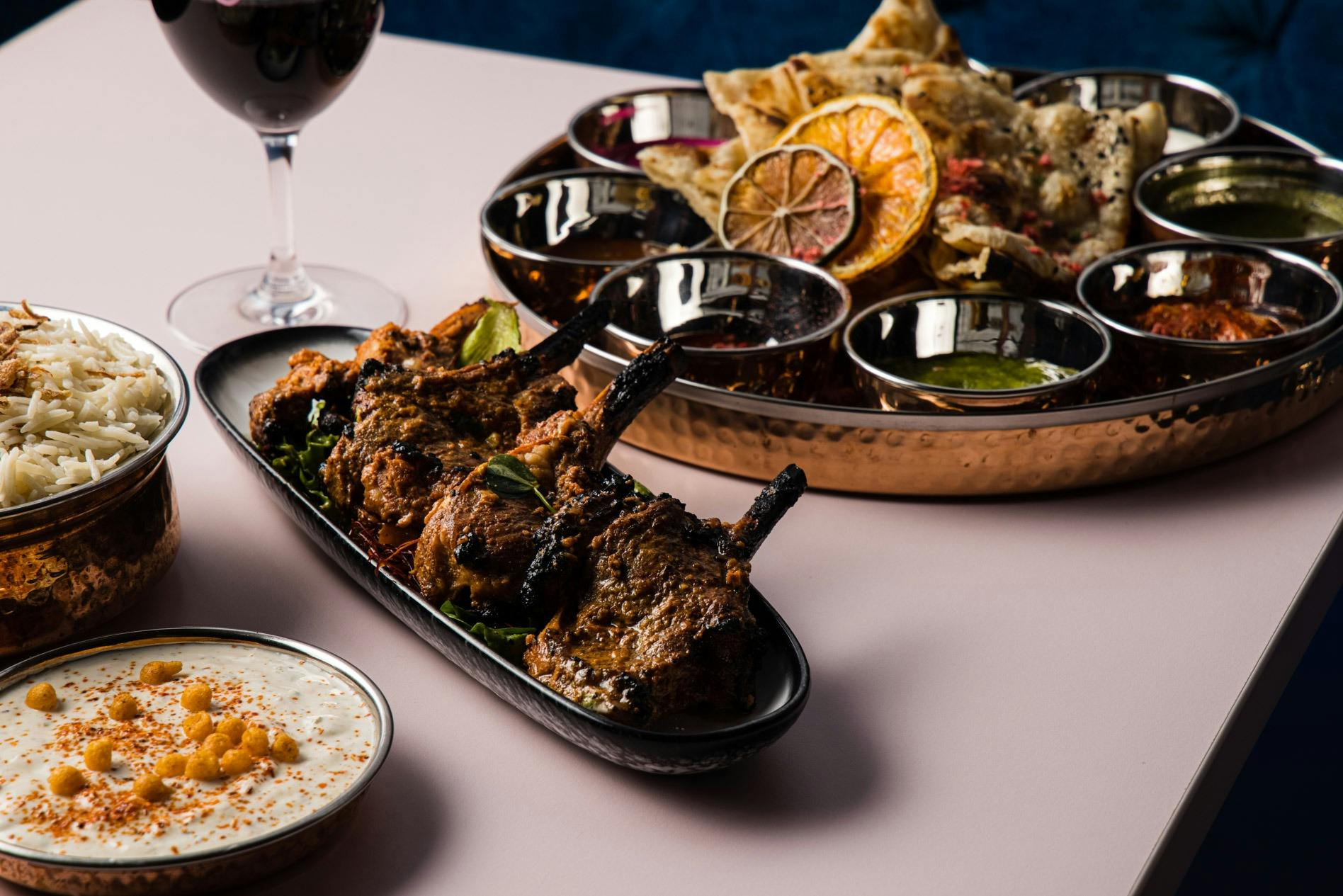 A plate of Lamb crops with a Thali (curry tasting plate) in the backrgound