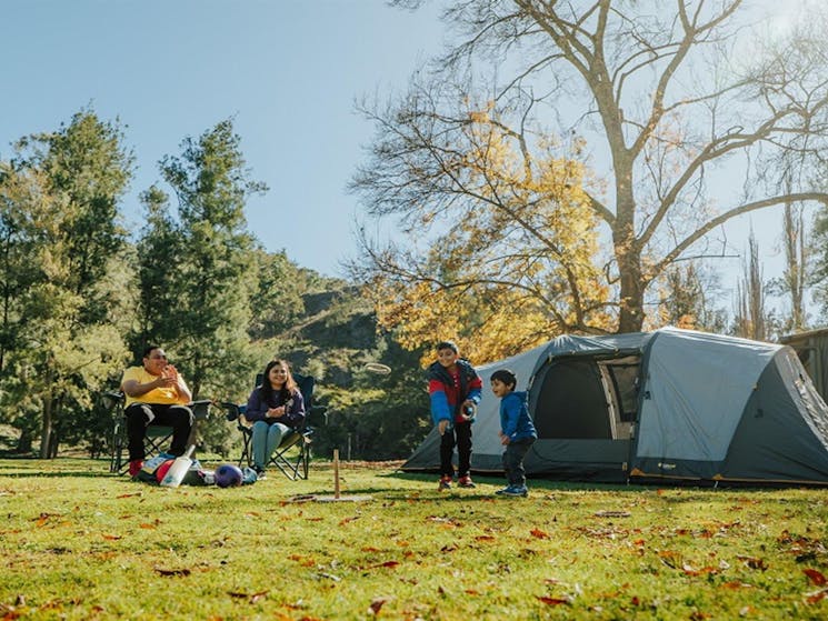 Kids play quoits beside their tent in Wombeyan Caves campground, as their parents look on. Credit: