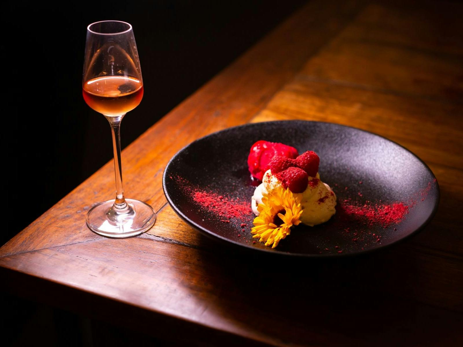 Wooden table with dessert wine glass and plated dessert with a flower