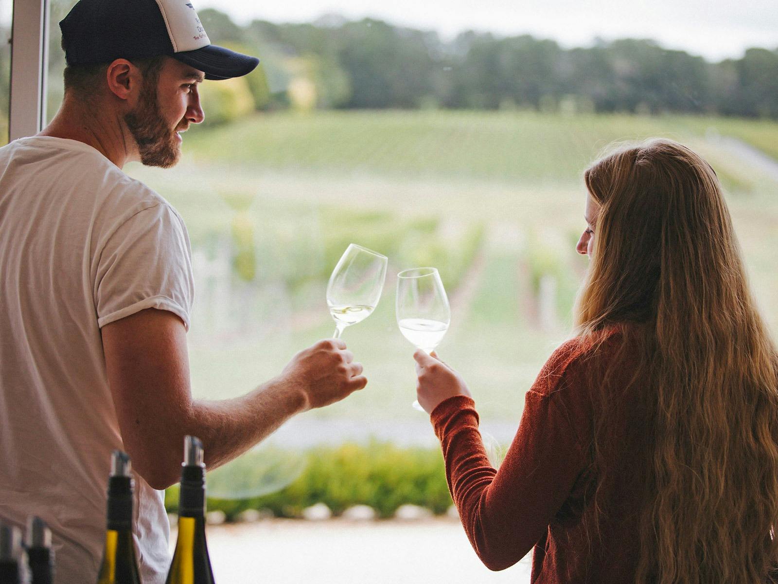 A man and a woman are enjoying a glass of wine in the Colmar Estate cellar door and clinking glasses