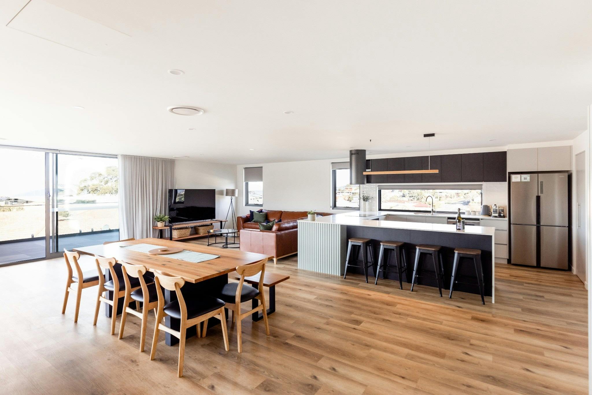 Spacious open-plan living featuring designer kitchen, large dining setting, comfortable lounge area