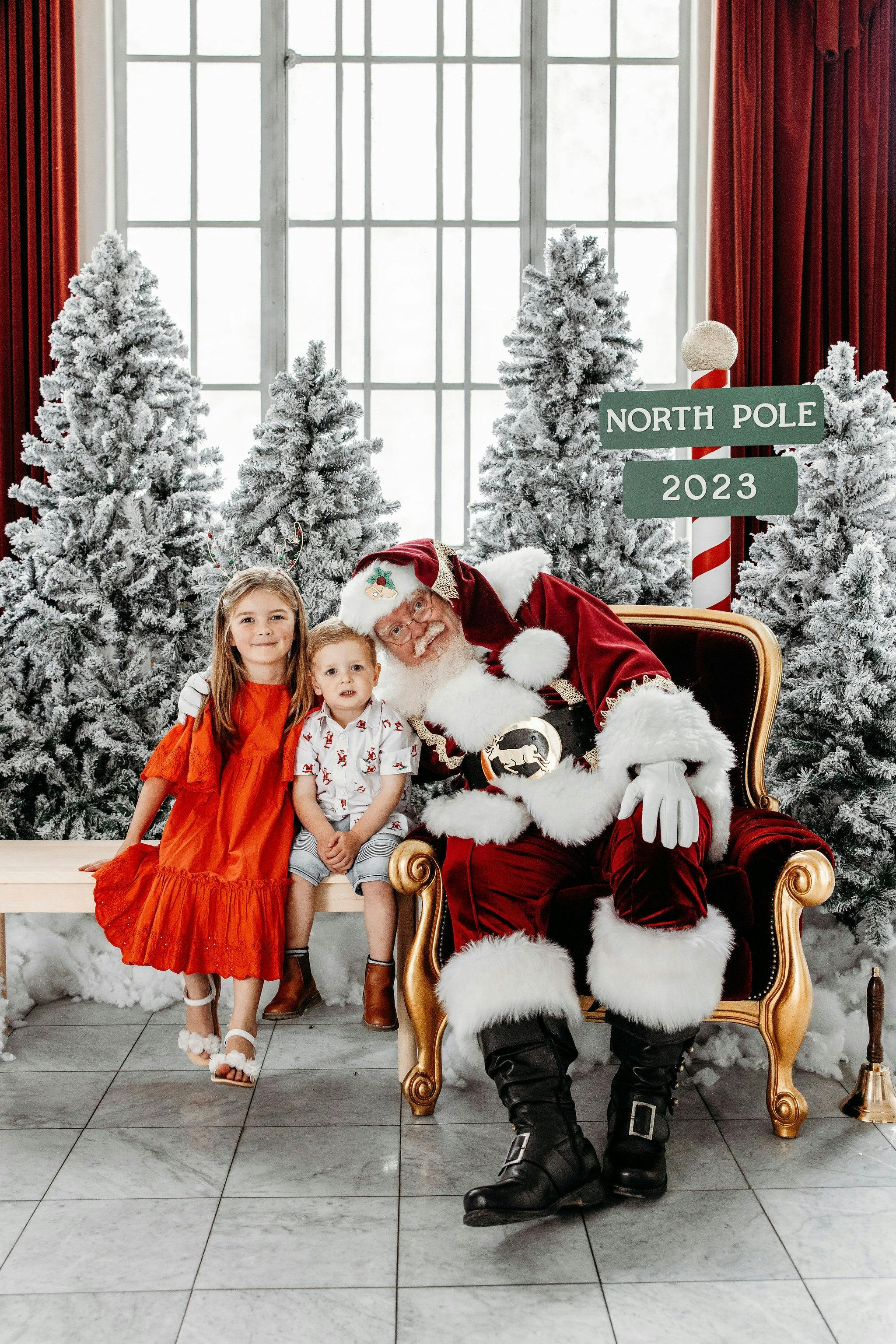 Santa with a child sitting on his lap. A family sitting with santa.