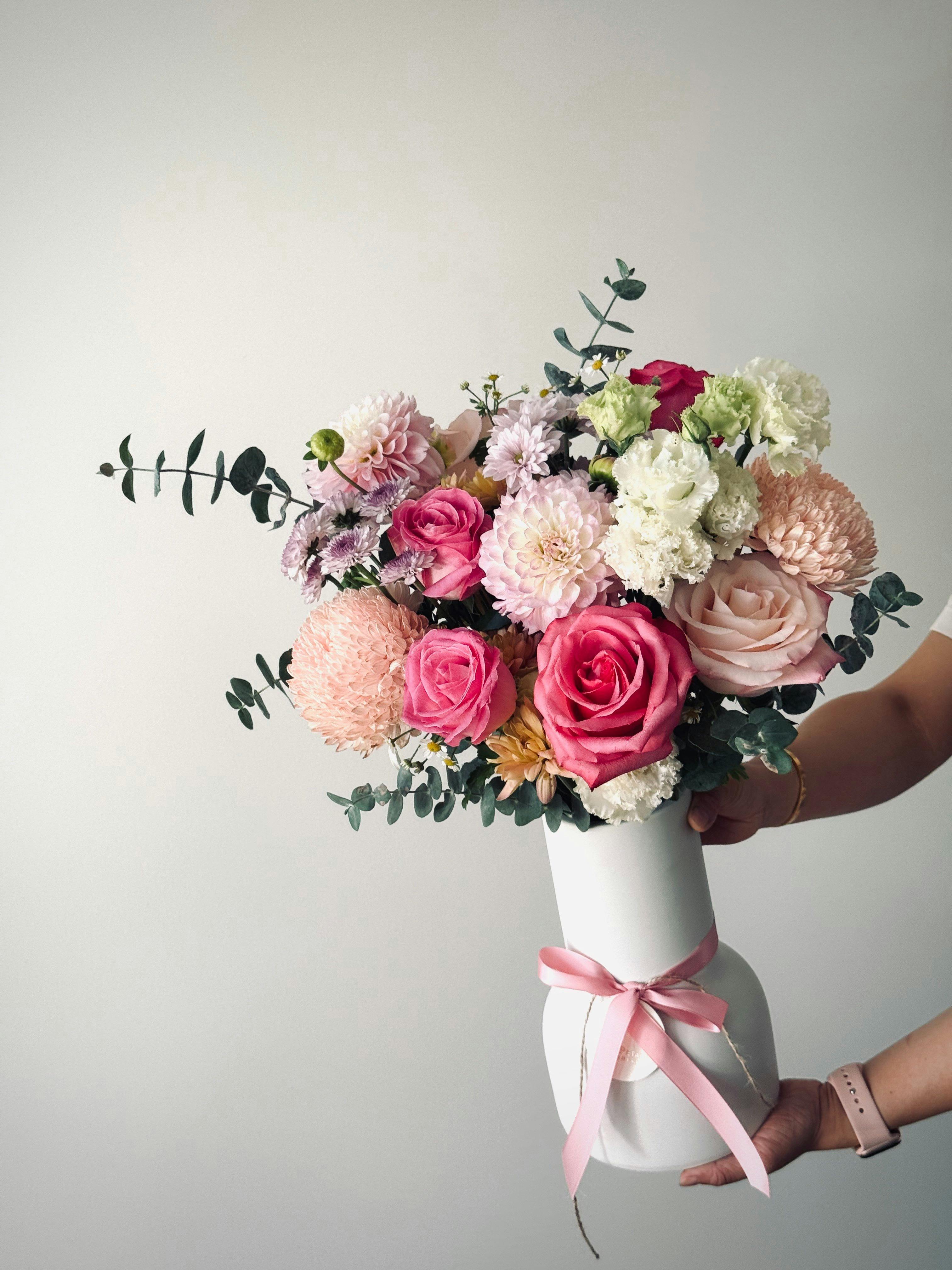 A seasonal colourful bunch of flowers arranged in a white vase.