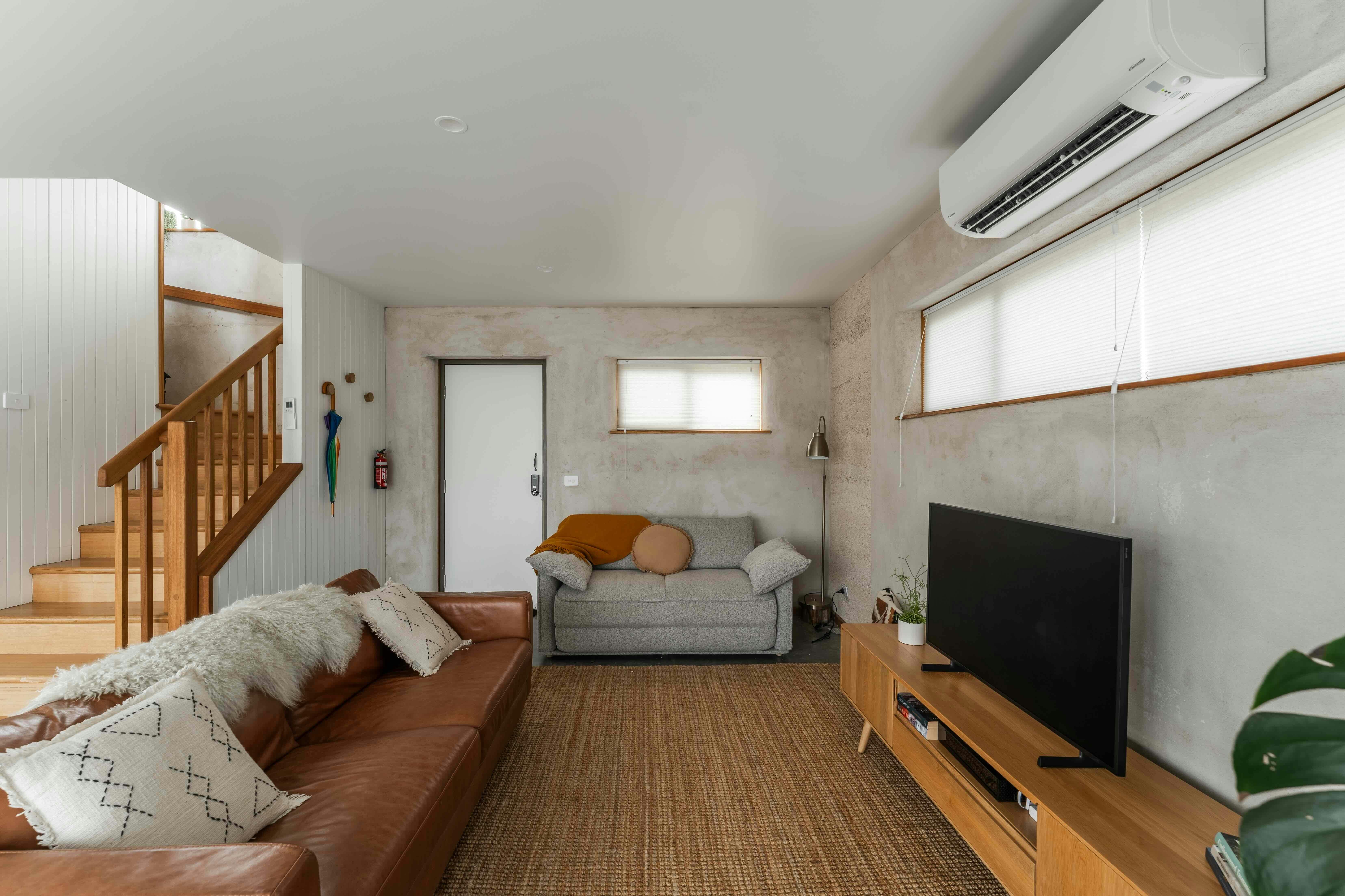 Couches with blankets and sheepswool, a TV and staircase leading to bedrooms.