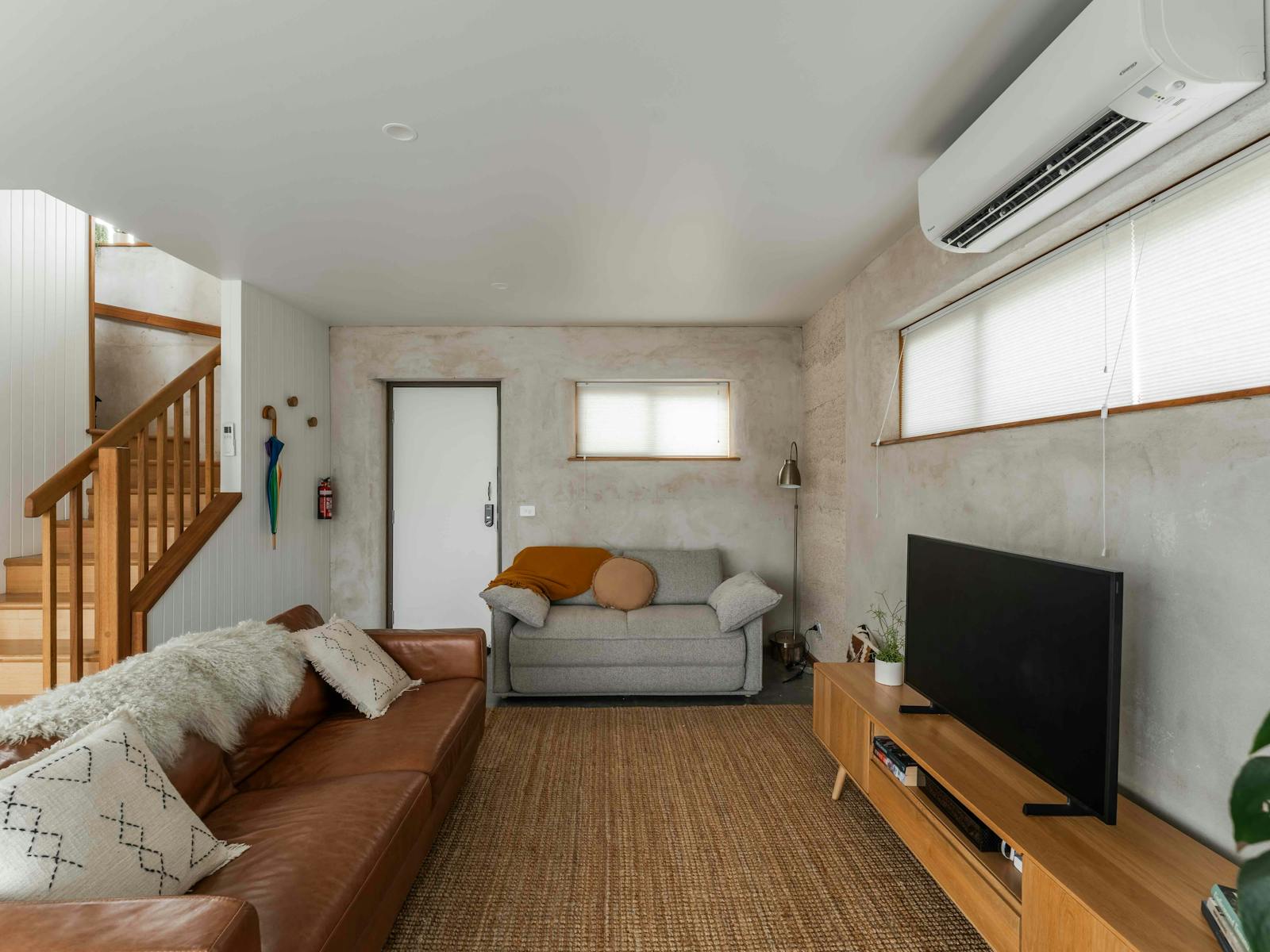 Couches with blankets and sheepswool, a TV and staircase leading to bedrooms.